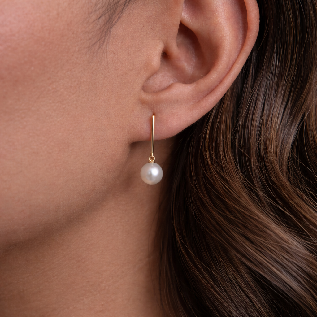 Pearl earring on a person's ear with a neutral background