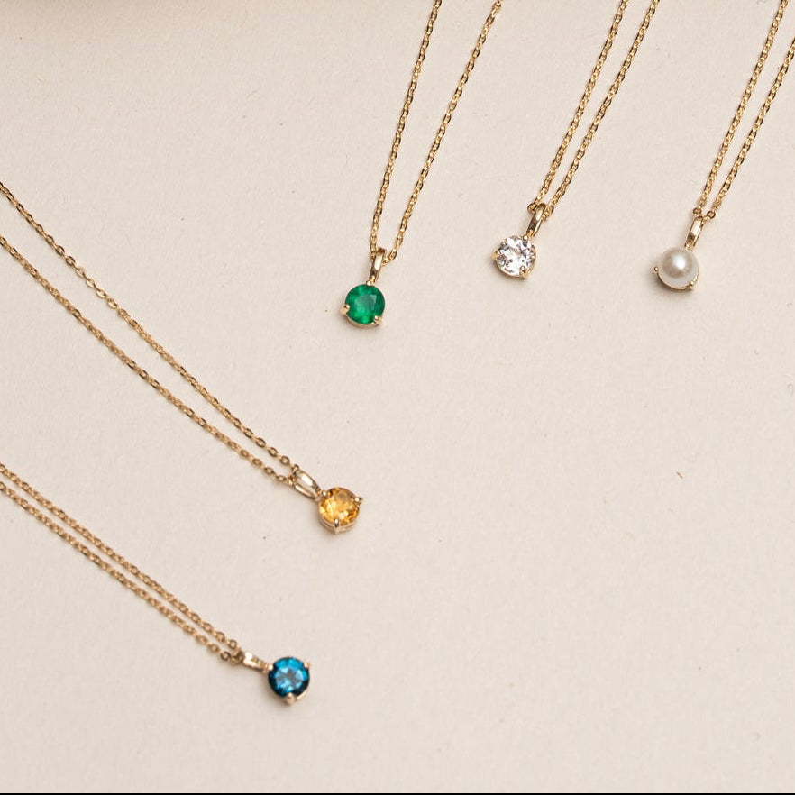 Necklaces with colorful pendants on a stone surface
