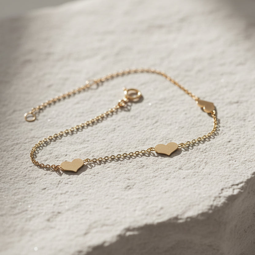 minimalist solid gold heart chain bracelet on rock