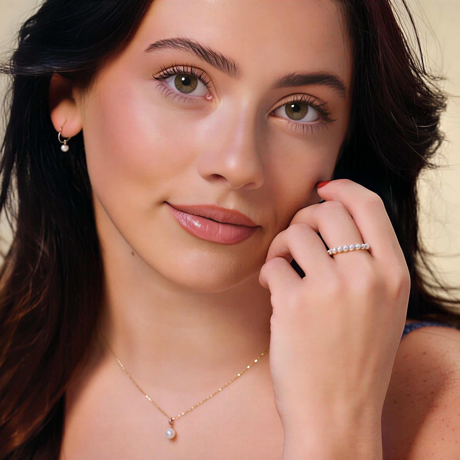 Woman wearing 14K yellow 12mm pearl earrings and a matching necklace with a neutral background.