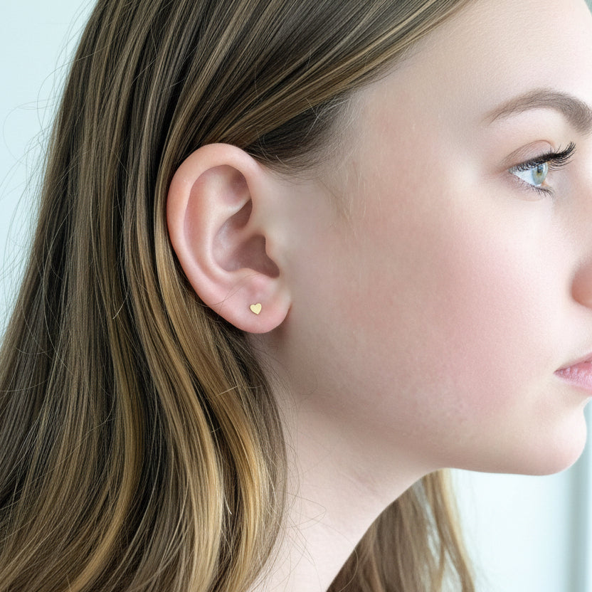 Close-up of an ear with a heart-shaped stud earring.
