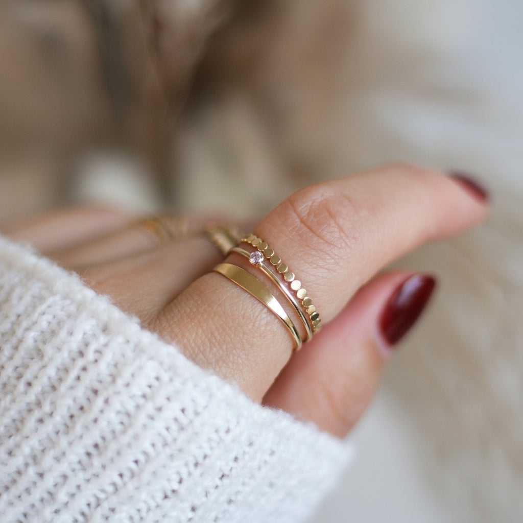 Close-up of a hand wearing gold rings with a blurred background