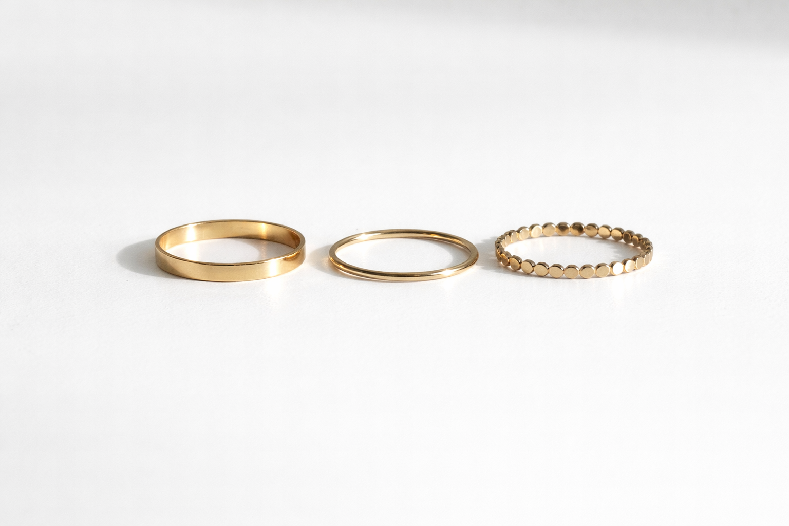 Three gold rings of different designs on a white background