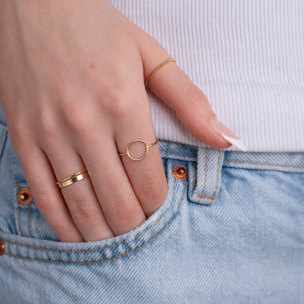 Close-up of a hand wearing gold rings with a light blue denim background