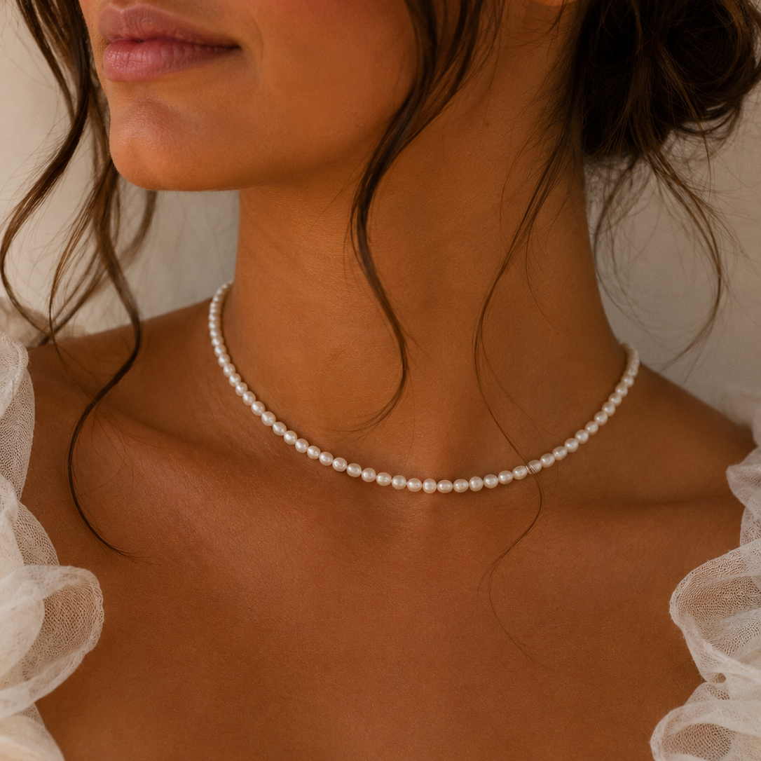 Close-up of a person wearing a pearl necklace with sheer white fabric in the foreground