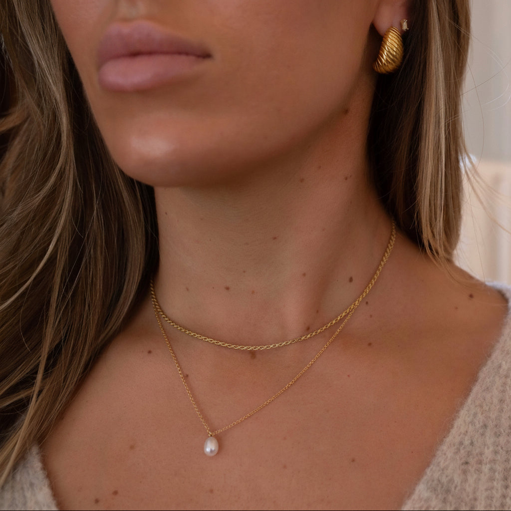 ered gold necklaces with pearl pendant and textured gold vintage earrings on model