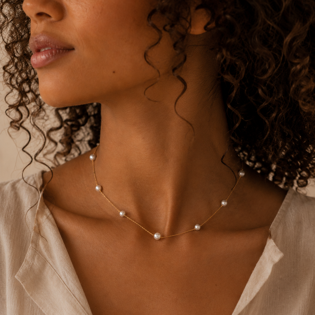Close-up of a woman wearing a delicate pearl necklace with a blurred background