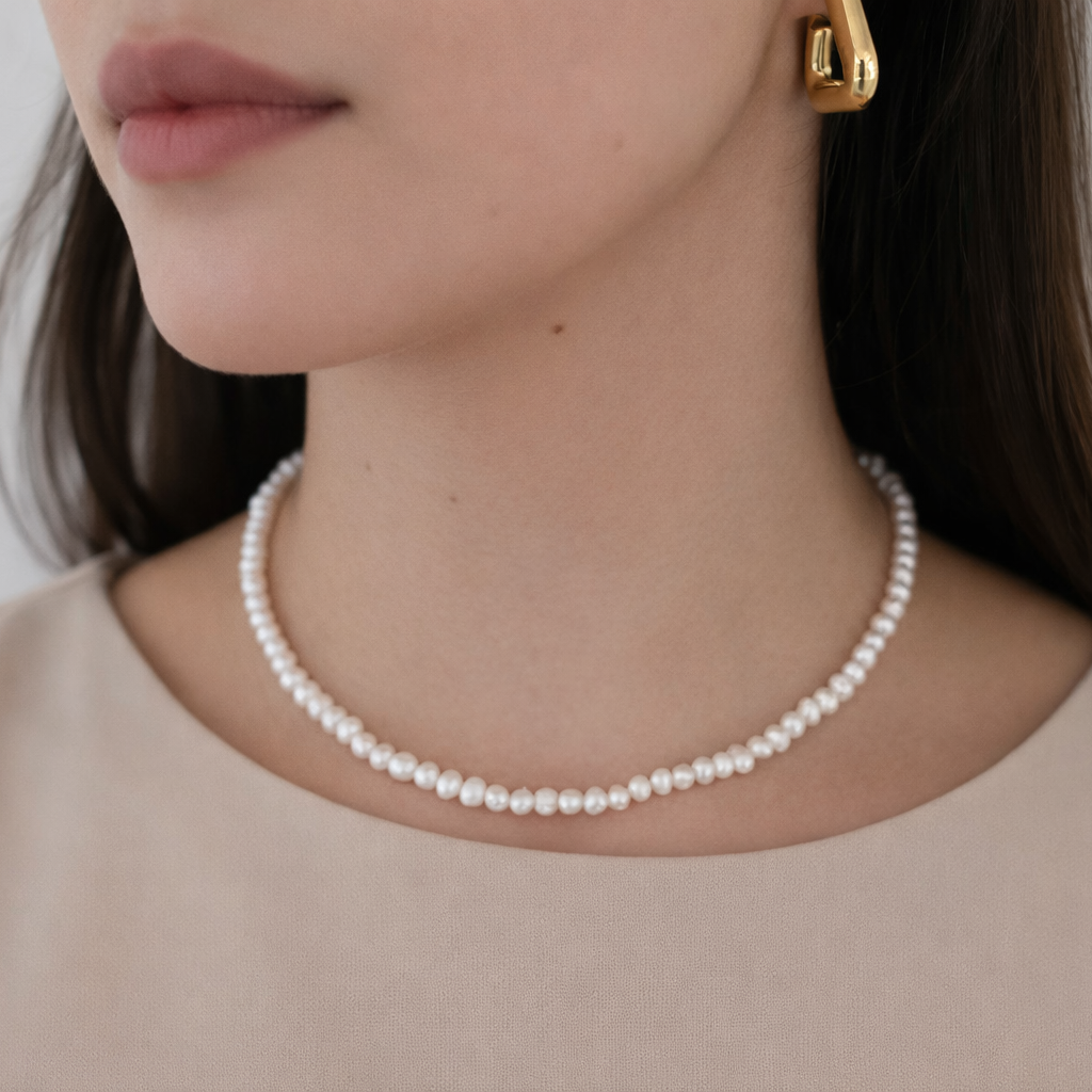 Pearl necklace worn by a person with a neutral background