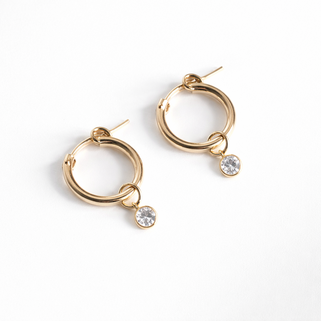 Gold hoop earrings with small round gemstones on a white background