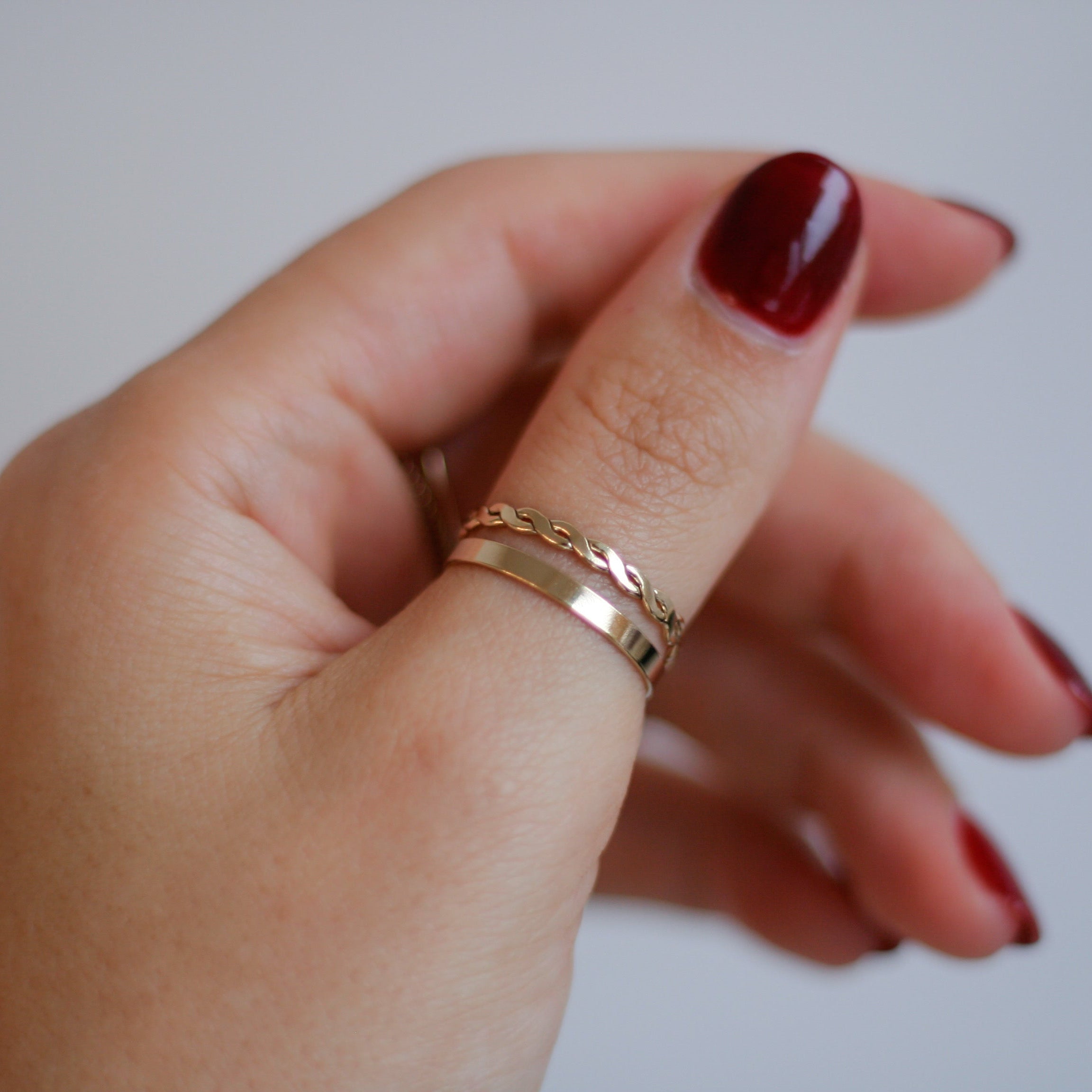 gold-filled braided ring stacked with a band on hand