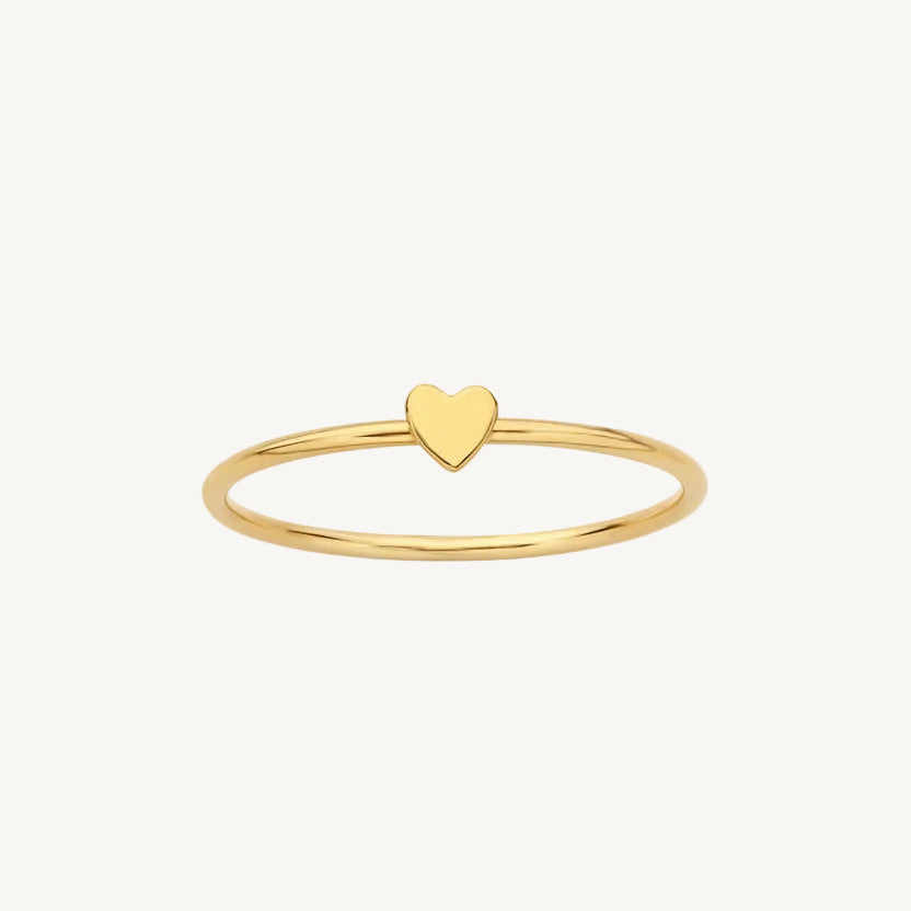 Gold ring with a heart-shaped charm on a white background