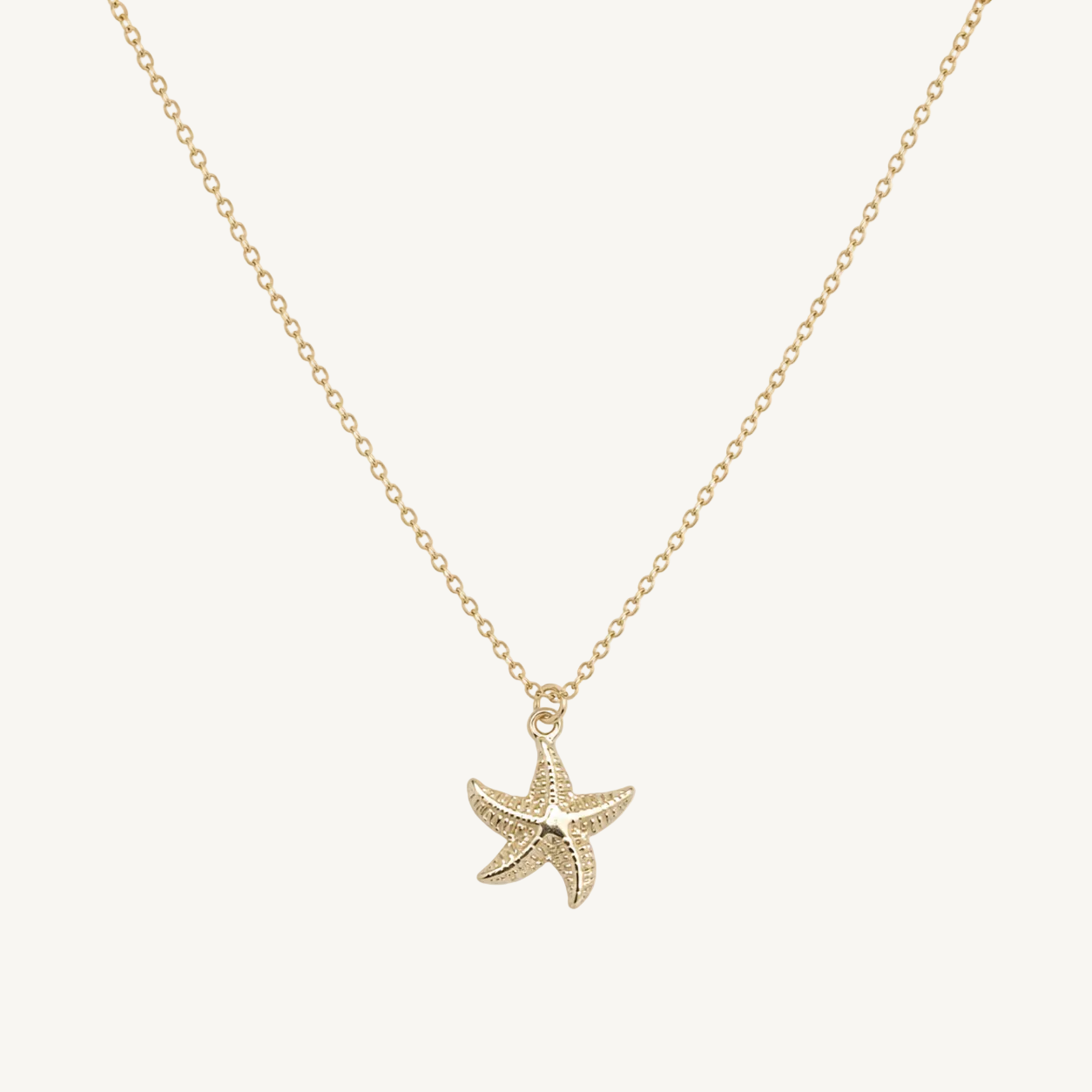 Gold starfish pendant necklace on a white background