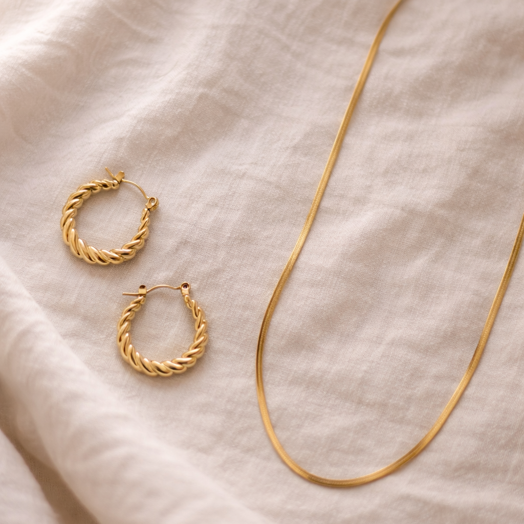close up shot of gold twist hoops and a dainty herringbone necklace