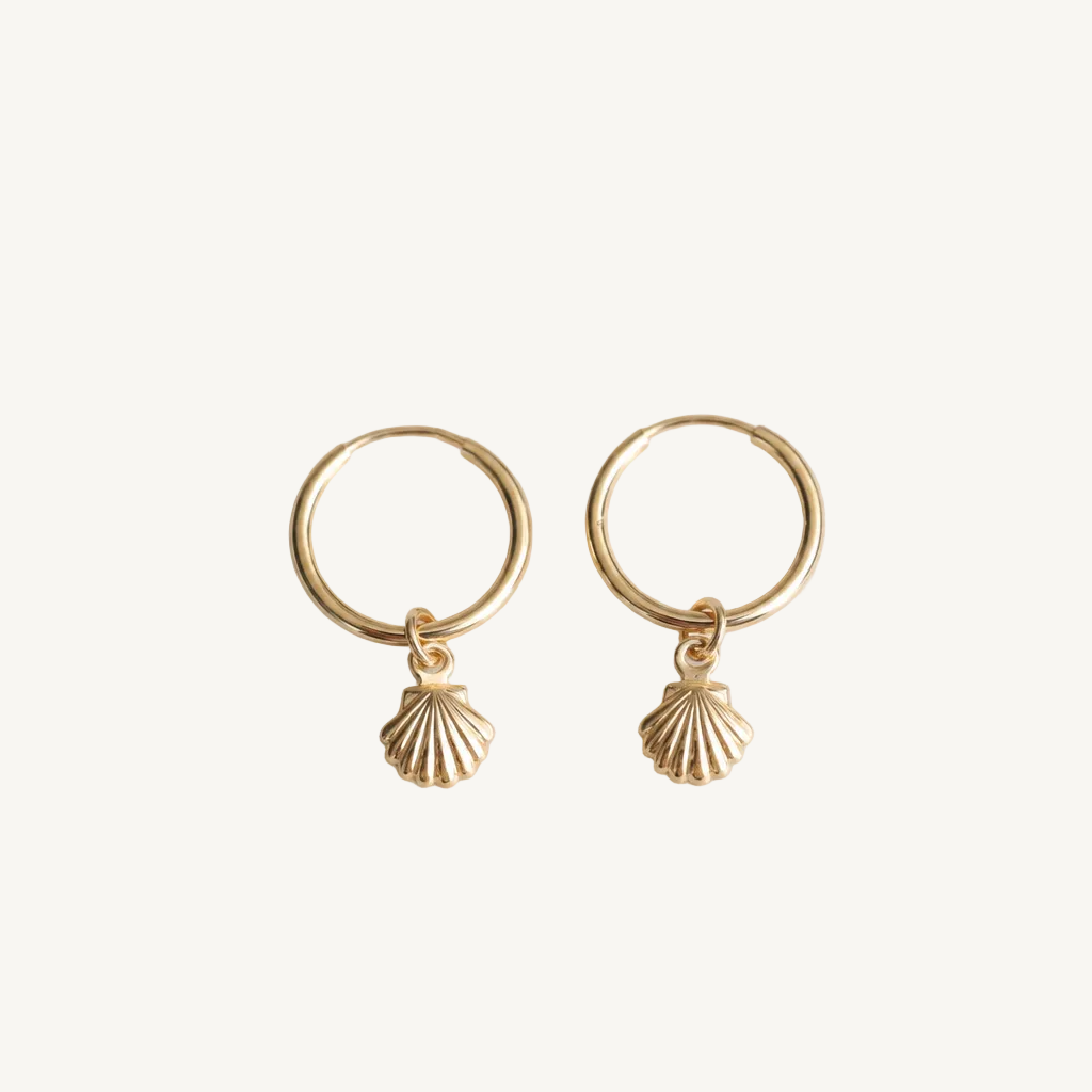 Gold hoop earrings with shell charms on a light gray background