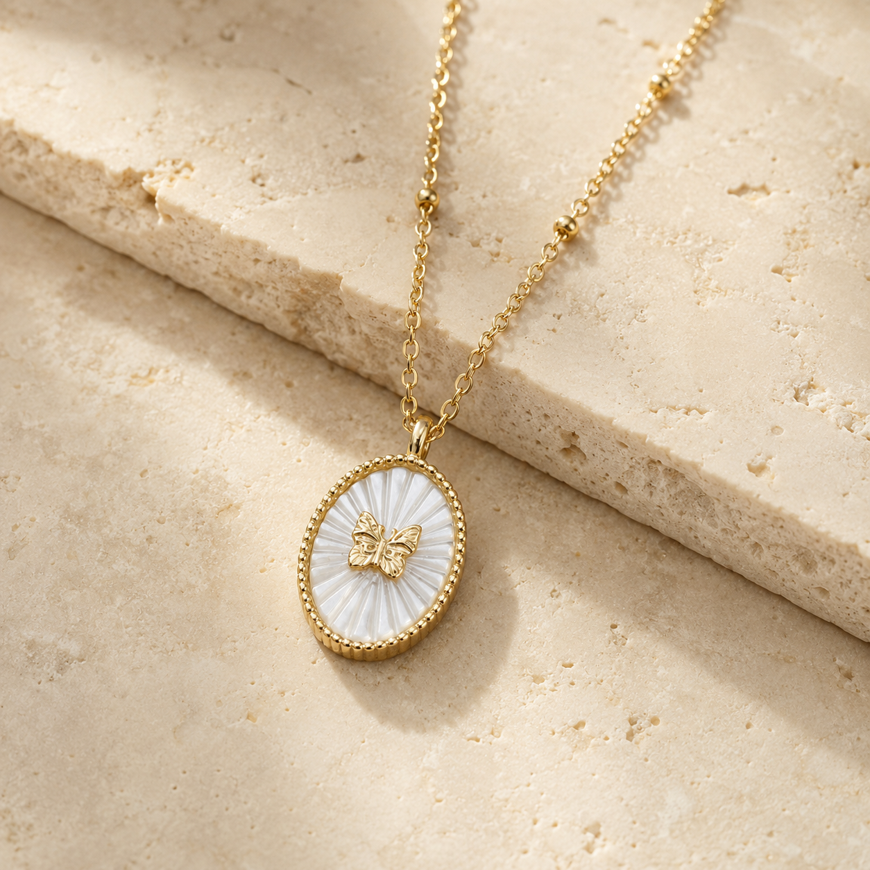Gold necklace with a butterfly pendant on a pearl stone surface