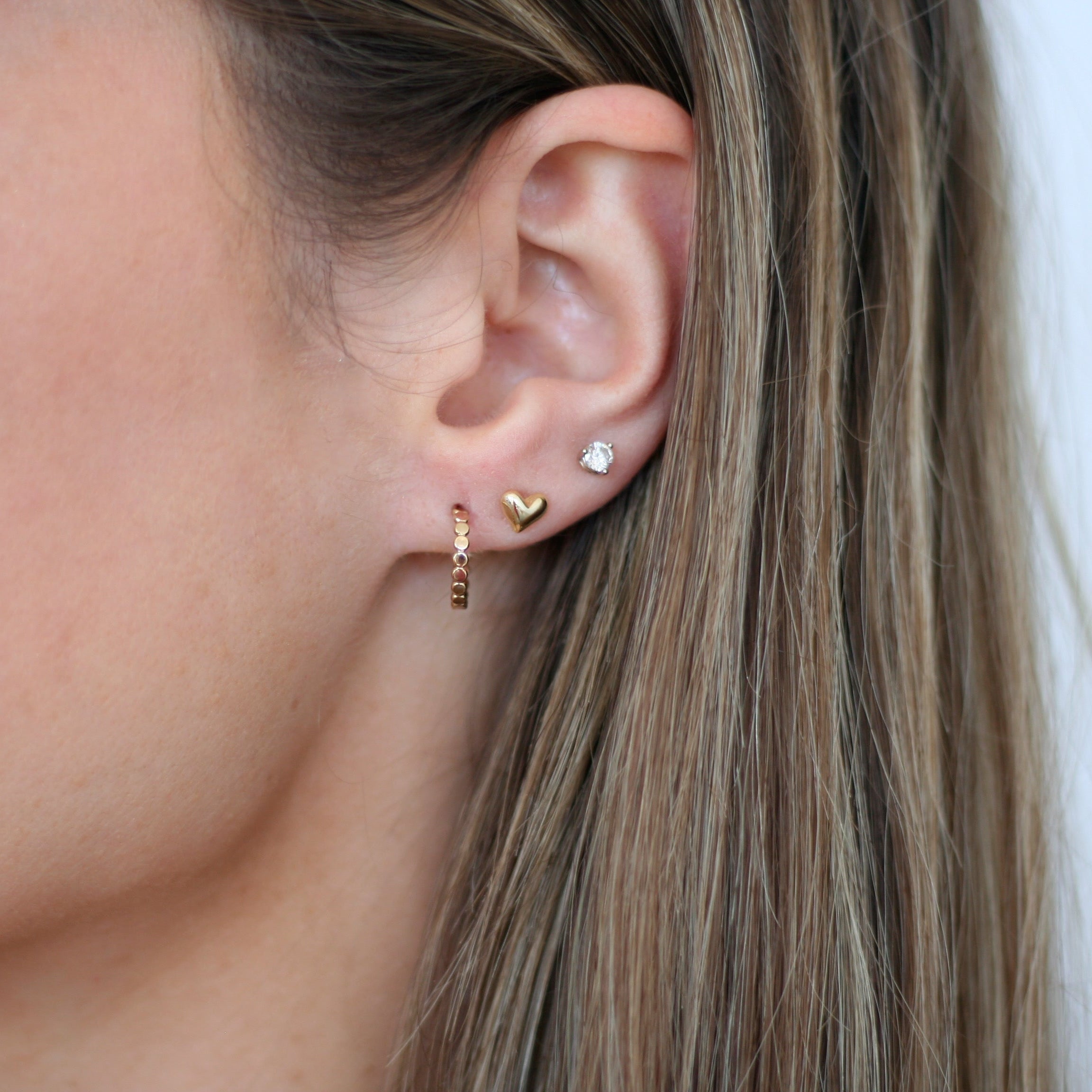 solid gold puffed heart flat back stud earring – on ear