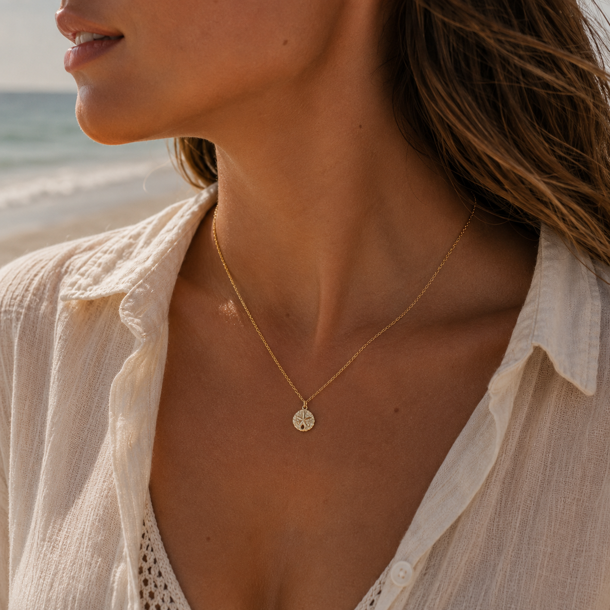 Woman wearing a gold necklace with a beach in the background