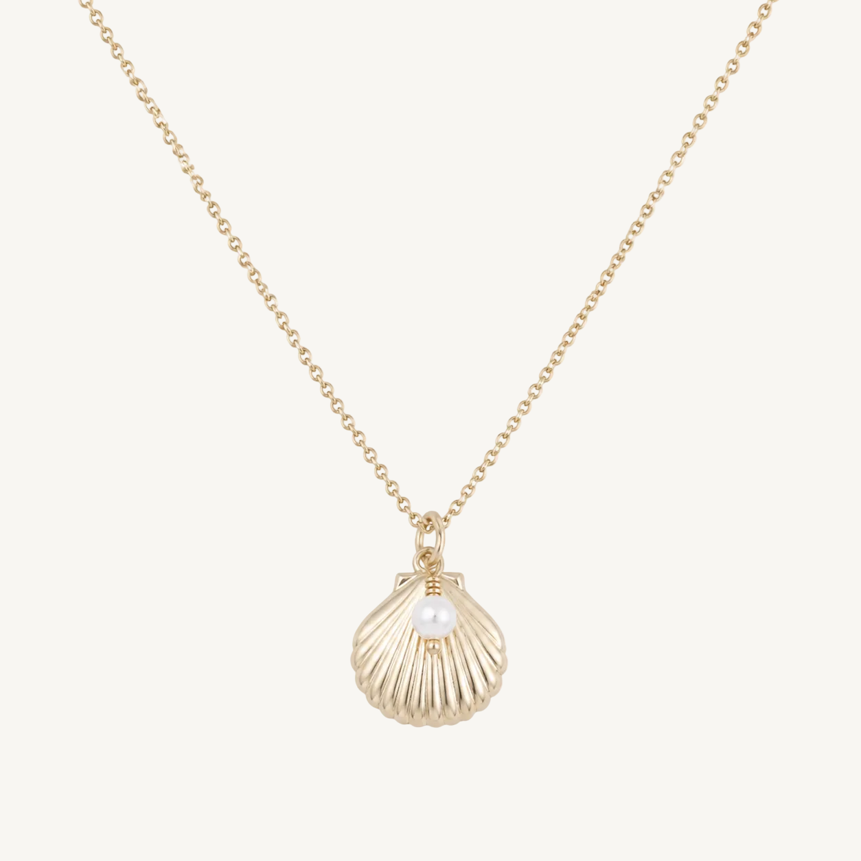 Gold necklace with a shell pendant and pearl on a white background