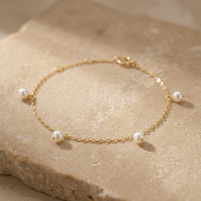 Gold bracelet with pearls on a beige stone surface